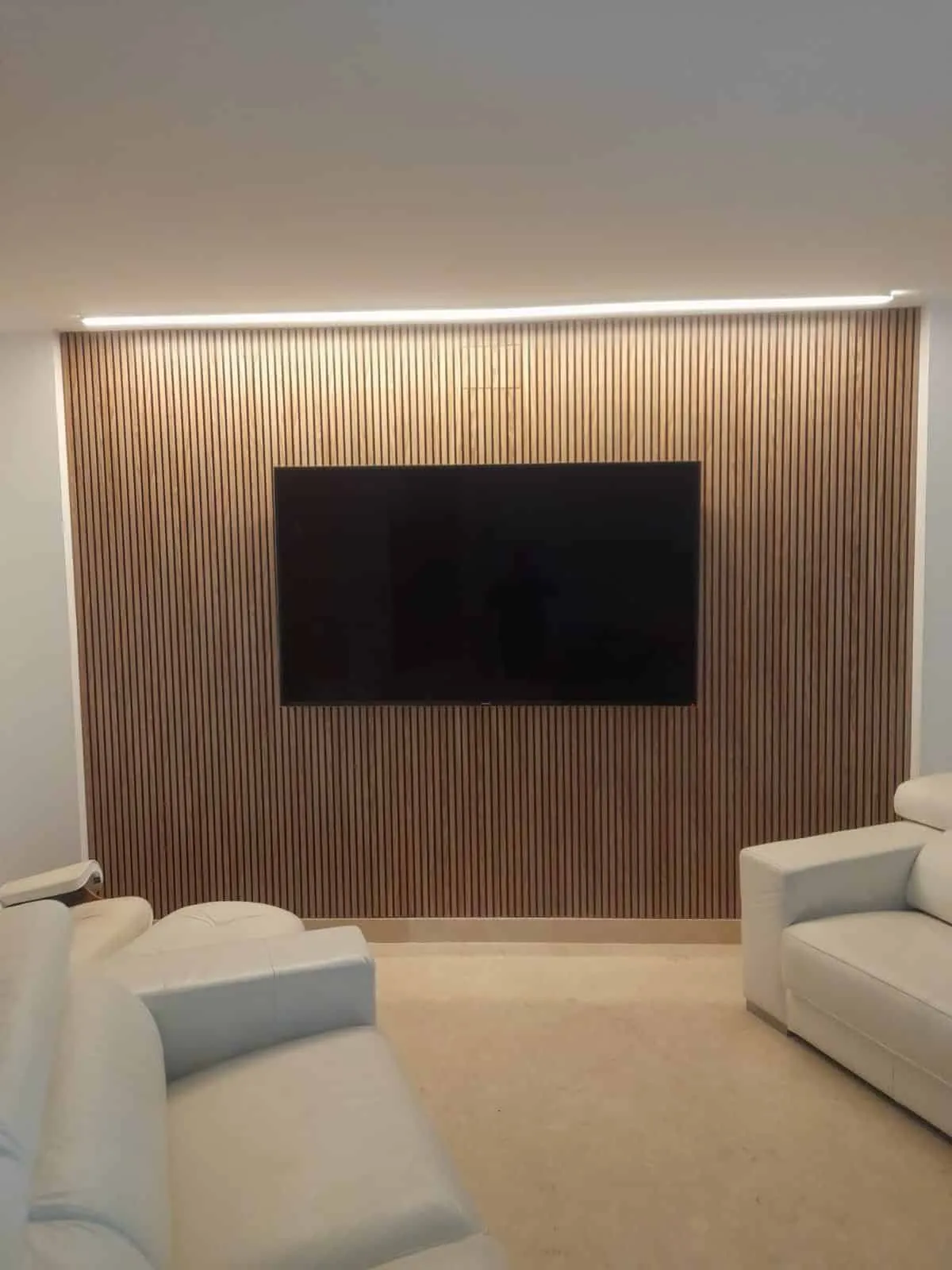 Trabajo real de TecniManitas: pared de listones de madera con TV colgada y tira LED en el techo